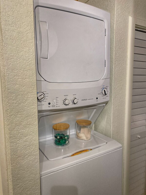 Una lavadora de carga frontal con un panel de control y dos frascos de vidrio en la puerta.