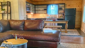 A cozy living room with a leather sofa, a small round table, and a patterned rug.