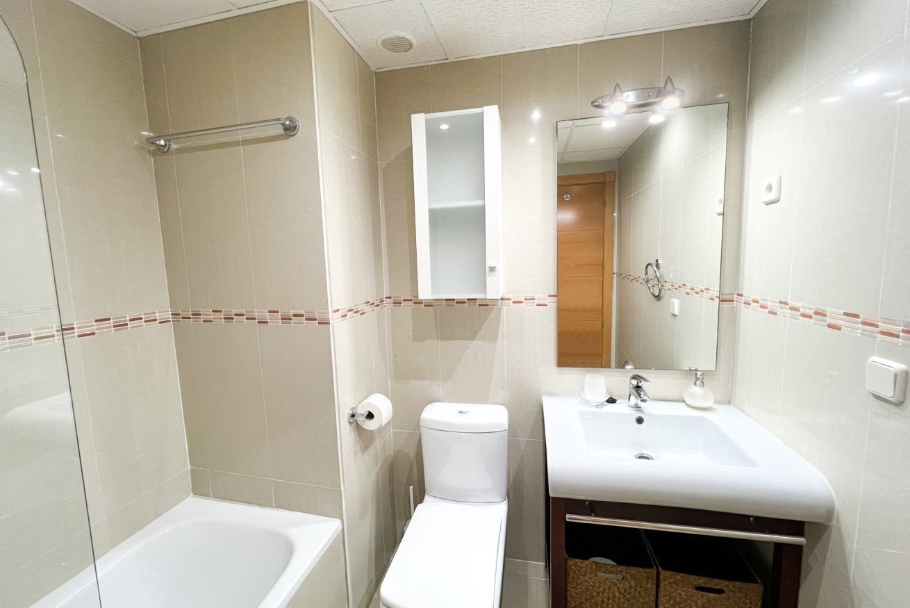 A bathroom with a bathtub, toilet, sink, and mirror.