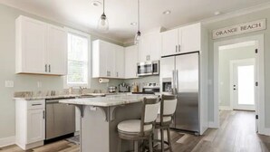 A modern kitchen with white cabinets, a stainless steel refrigerator, and a marble countertop.
