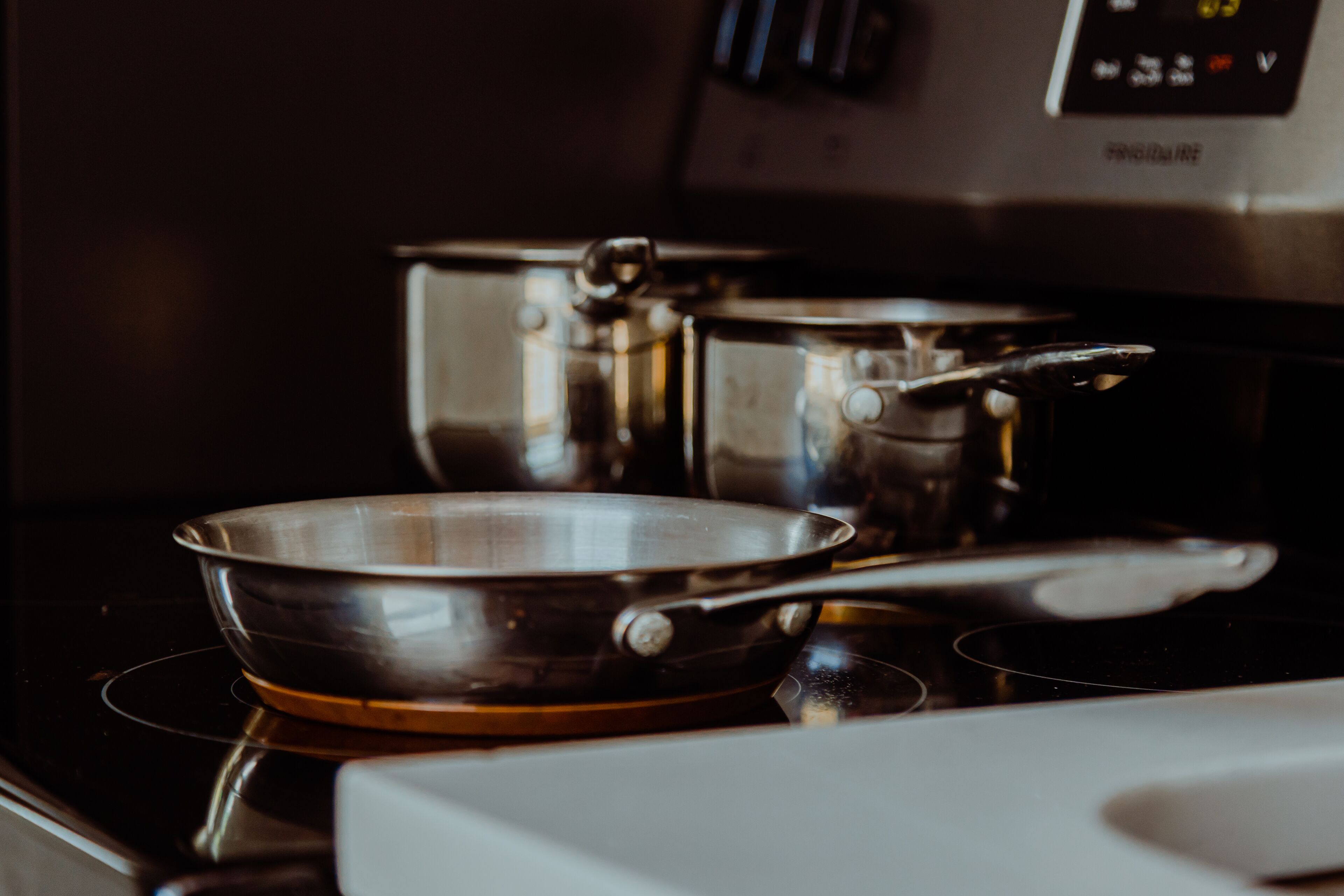 A kitchen with a stainless steel pan on an induction cooktop.