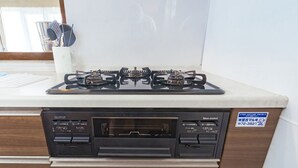 A kitchen with a gas stove, oven, and dishwasher. There is a window with a view of the outside.