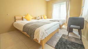 A hotel room with two beds, a chair, and a large window with curtains.