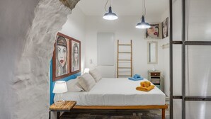 A bedroom with a bed, a wooden nightstand, a lamp, a ladder, and artwork on the wall. - Casetta PesceBlu, a stay with a unique style (Trieste)