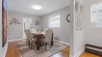 Un comedor con una mesa de madera, cuatro sillas y un tapete estampado.