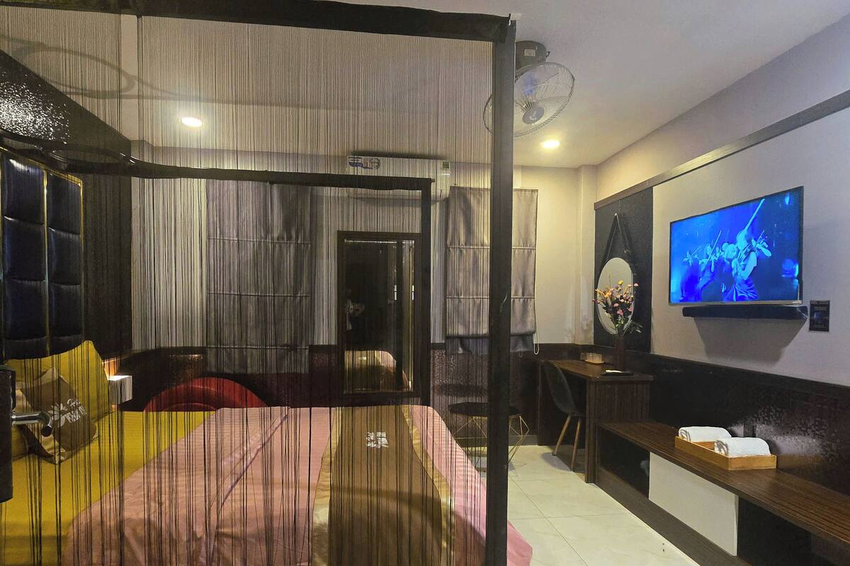 Habitación de hotel moderna con una cama grande, un televisor montado en la pared y un escritorio con una silla.