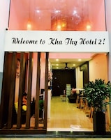 La entrada del hotel Kha Thy 2, con un mostrador de recepción, zona de estar y una planta grande en maceta.