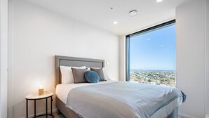 Una camera moderna con un letto grande, un comodino e vista su un paesaggio lontano attraverso un'ampia finestra.