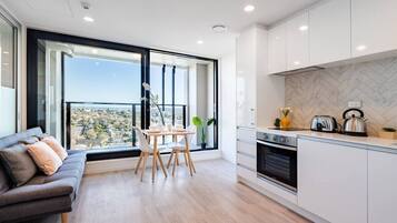 A modern kitchen with a built-in oven, a dining table with chairs, and a sofa.