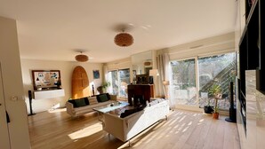 A spacious living room with a sofa, a coffee table, and a surfboard decoration on the wall. - Splendid House, Jacuzzi and Private Gardens Paris (Boulogne-Billancourt)