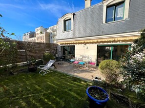 A residential property with a backyard patio, a wooden fence, and a small garden area.