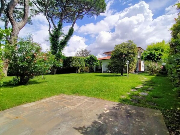 A well-maintained garden with a stone pathway leading to a house with a red roof. - Villa Martino by Interhome (Forte dei Marmi)