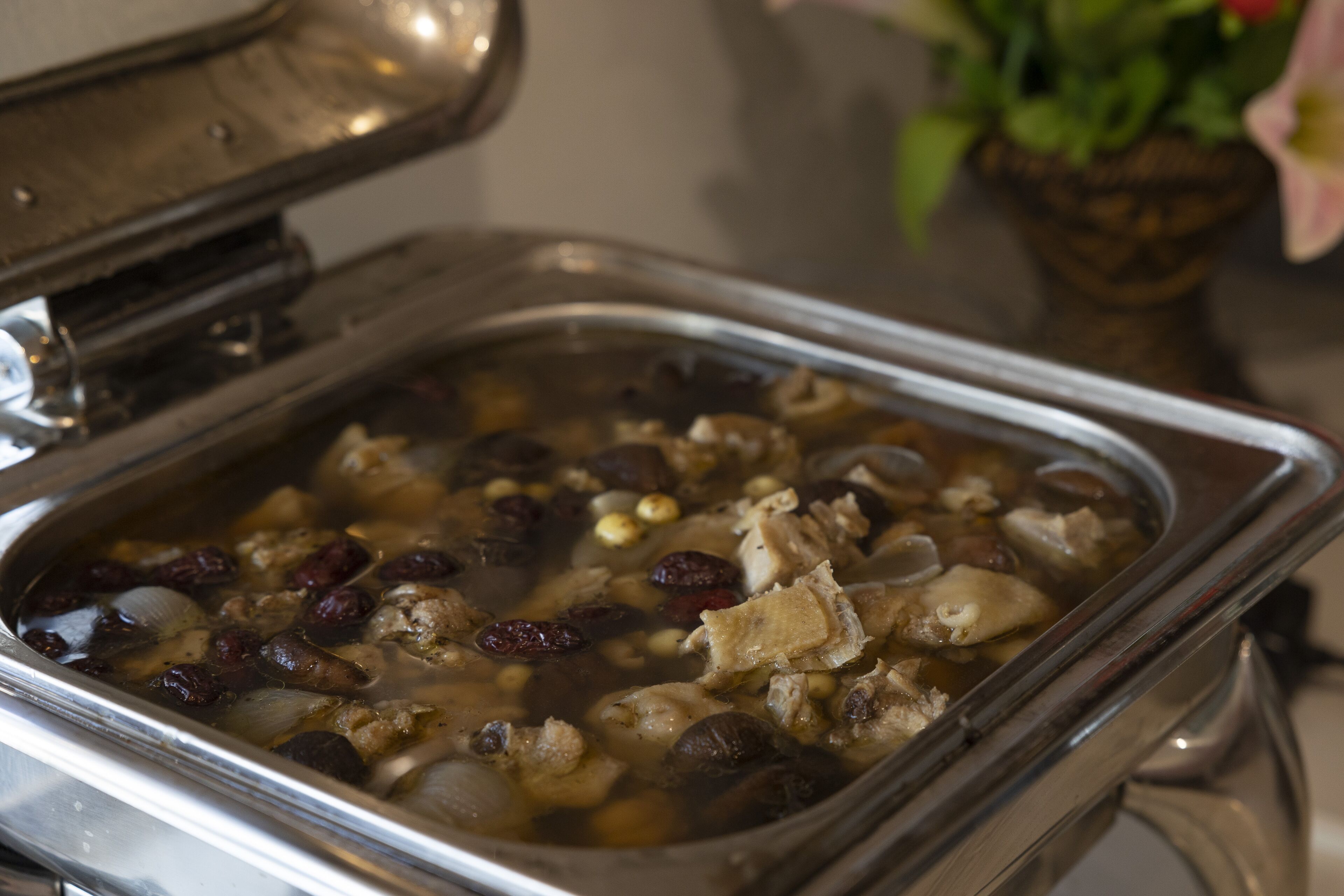 Un buffet proposant une variété de plats, notamment des viandes, des légumes et des fruits, présentés dans un plat de service en métal.