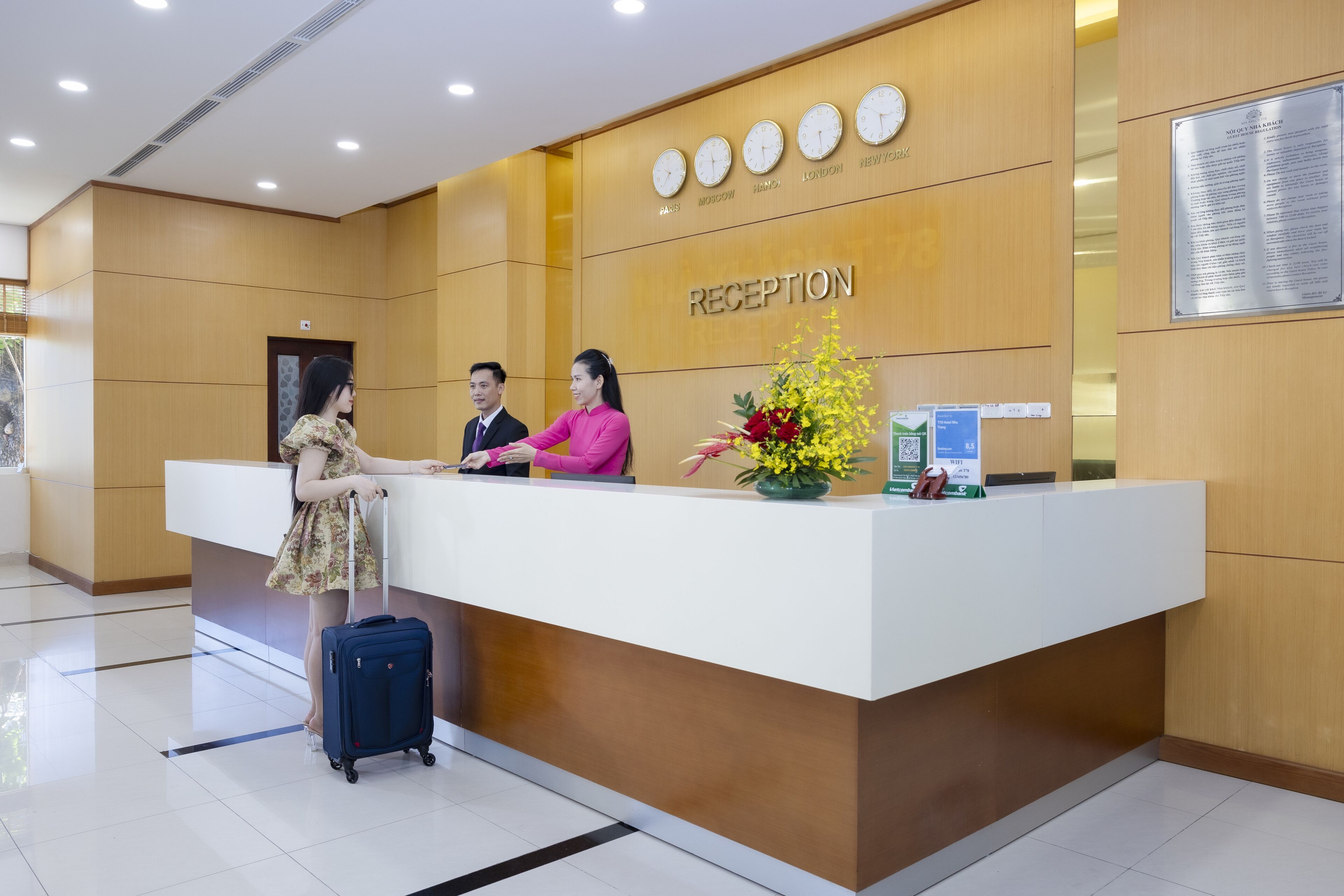 A reception desk with a wooden panel wall, clocks, and a plaque.