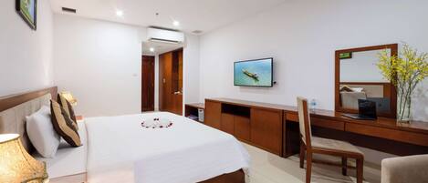 A hotel room with a bed, desk, chair, TV, and a mirror.