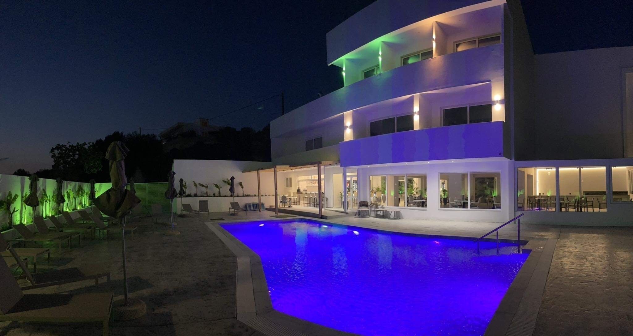Un edificio moderno a due piani con piscina esterna illuminata da luci blu.
