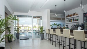 A modern bar area with a pool view, bar stools, and a well-stocked shelf of beverages. - Fresh hotel rhodes (Rhodes)