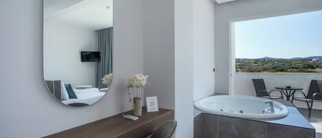 Une salle de bain moderne dotée d’un grand miroir, d’un meuble-lavabo avec un vasque plate, d’une baignoire et offrant une vue sur l’extérieur.