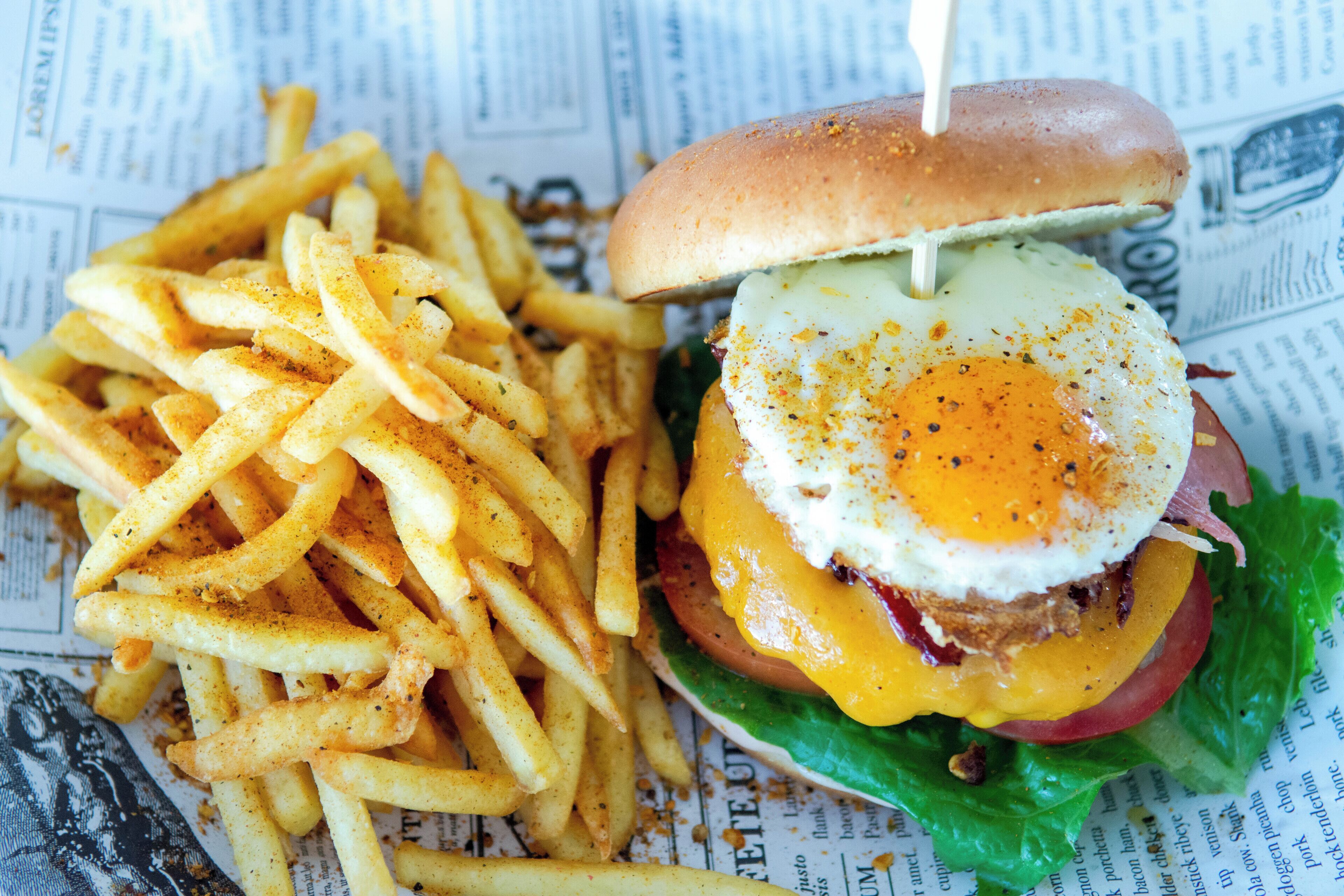 Ein Burger mit Spiegelei und Käse, dazu gewürzte Pommes.