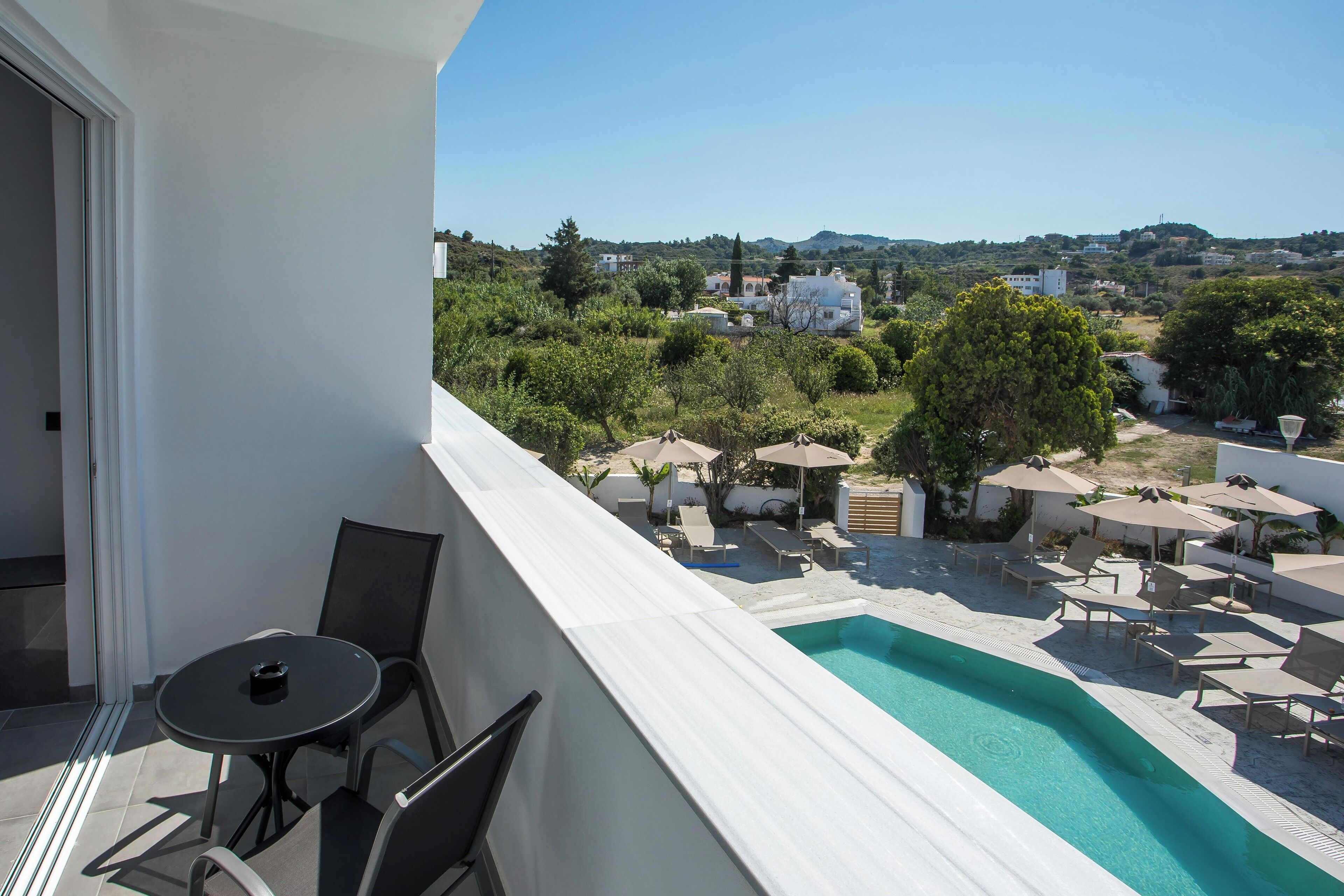 A balcony with a pool, chairs, and umbrellas.
