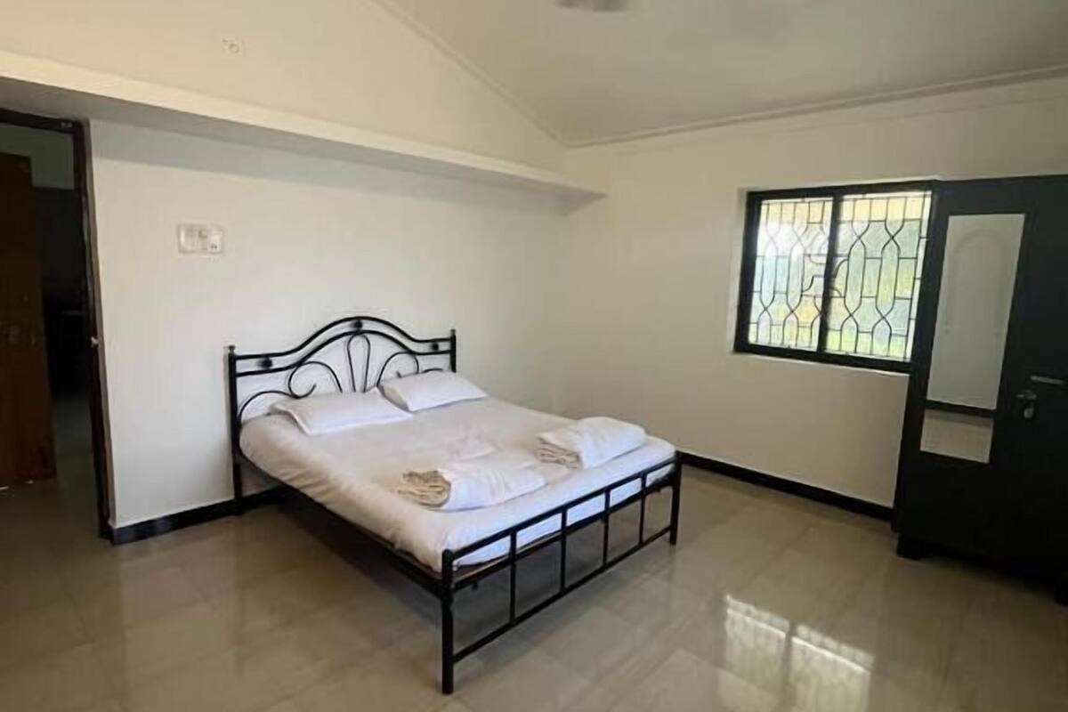 Ein Schlafzimmer mit einem Bett, einem Deckenventilator, einem Fenster mit dekorativem Gitter und einem Kleiderschrank.