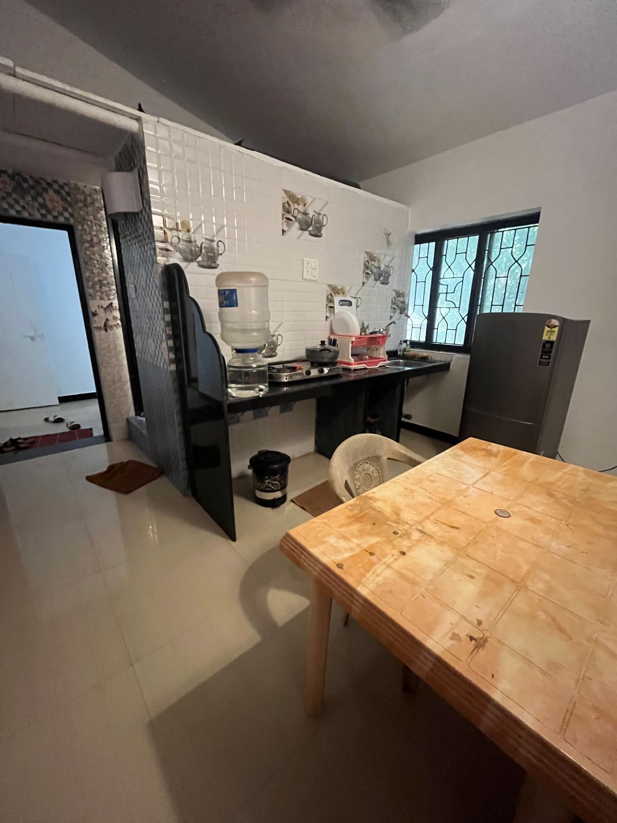 Una cocina compacta con una mesa de comedor, dispensador de agua, cafetera y refrigerador.