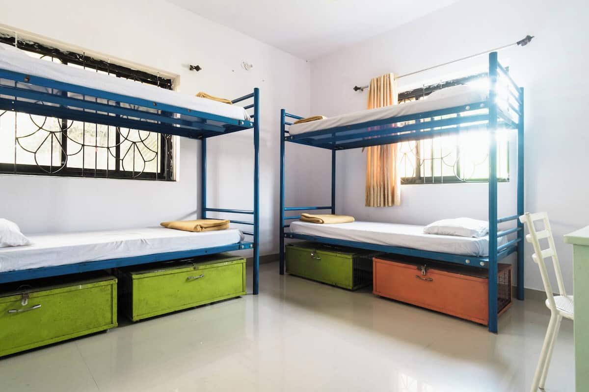 Ein Schlafsaalzimmer mit Etagenbetten, Stauraumschränken und einem vergitterten Fenster.