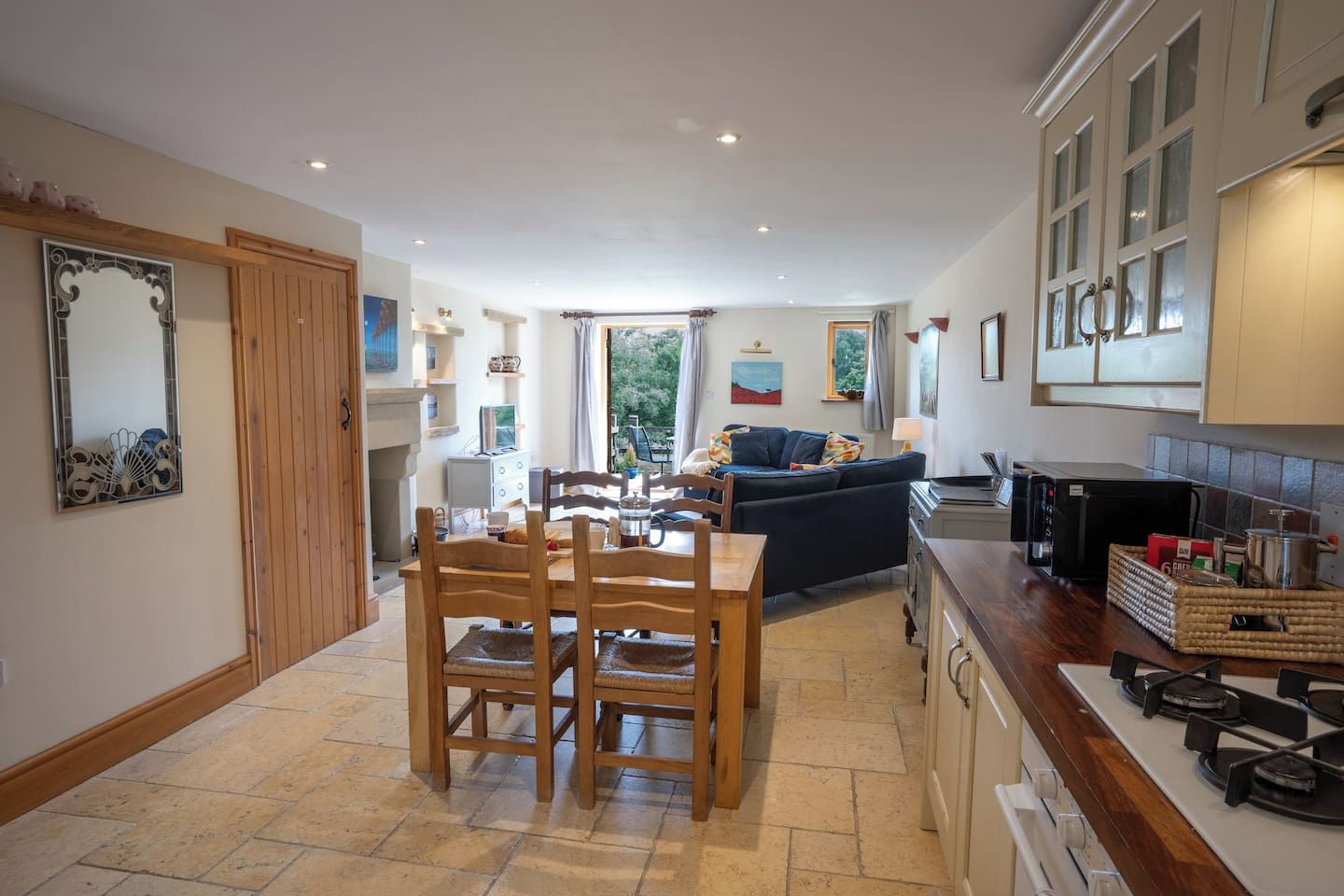 A compact kitchen with a dining area, a sofa, and a view of the outdoors.