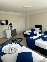 Quarto de hotel com duas camas, televisão, penteadeira e uma porta.