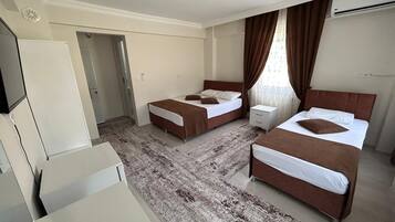 A hotel room with two beds, a desk, a wardrobe, and a bathroom.