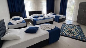 A hotel room with three beds, a large window with curtains, a patterned rug, and a wardrobe. - Paradise House  (Denizli)