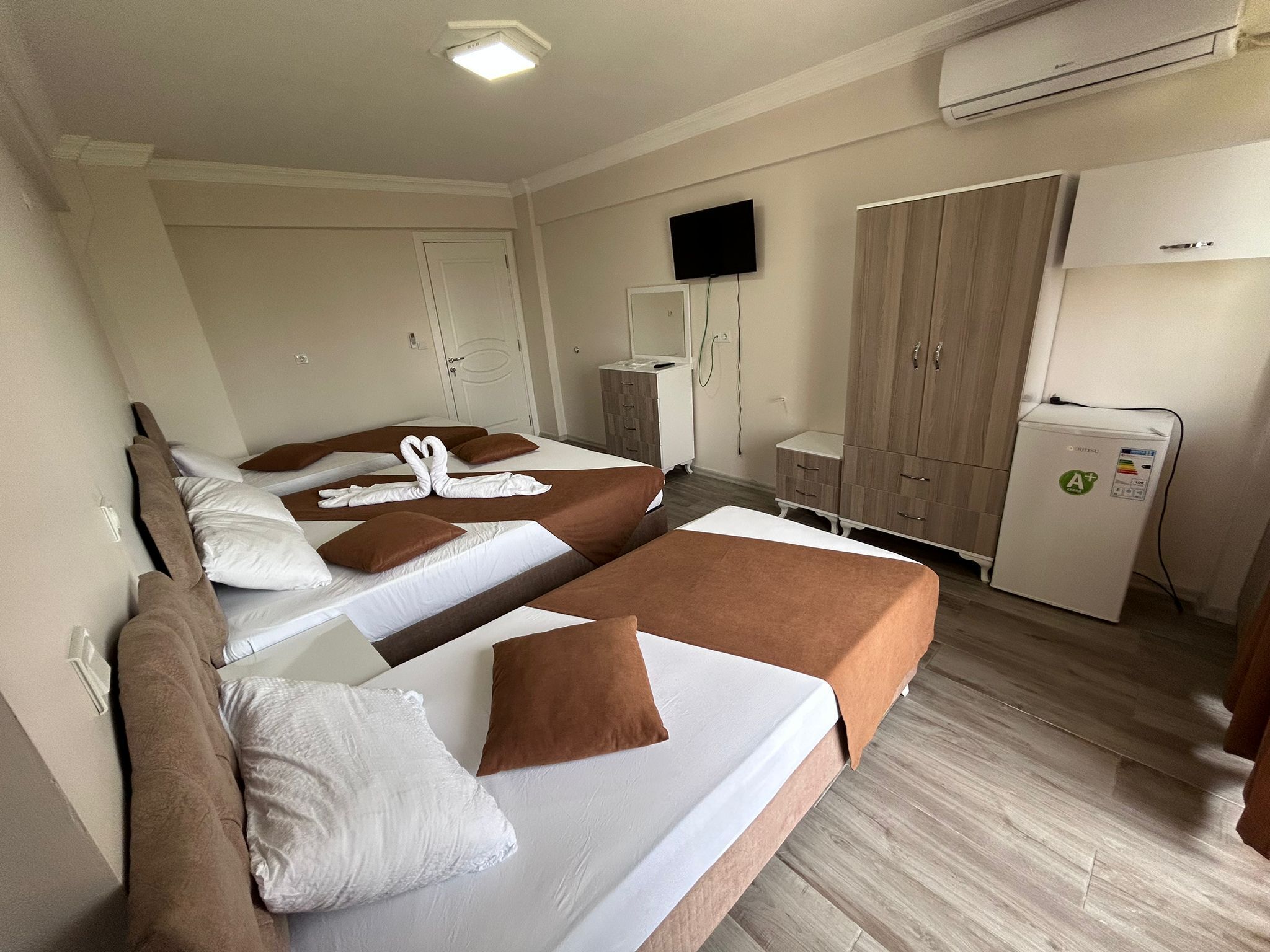 A hotel room with two beds, a TV, a wardrobe, and a mini-fridge.