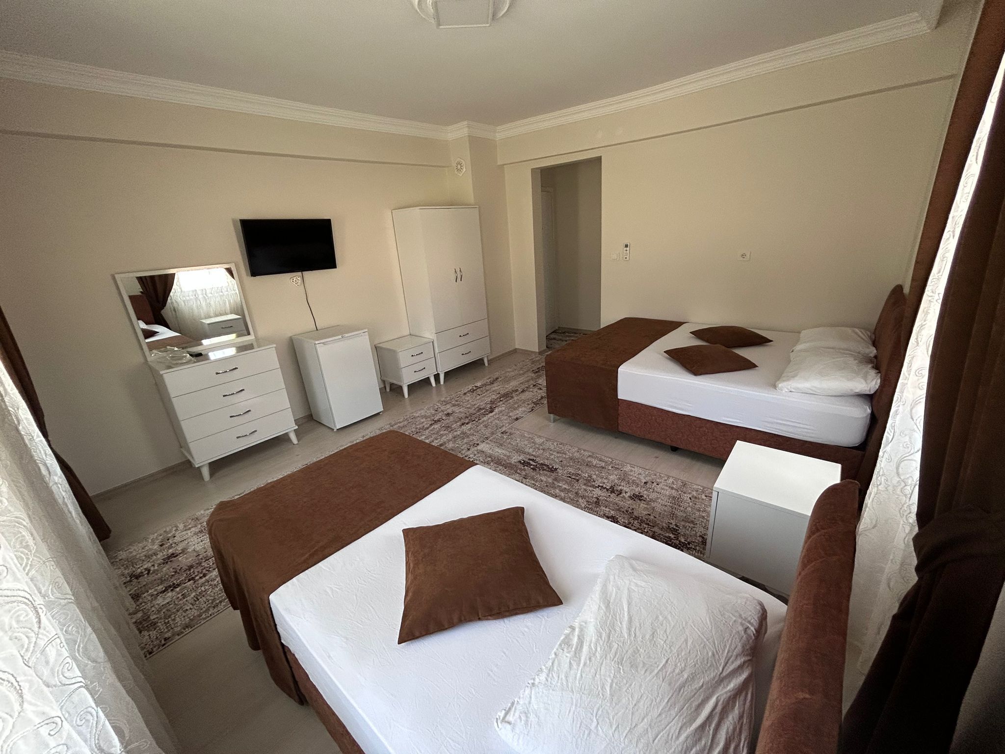 Una habitación de hotel con dos camas, un armario, un televisor y un escritorio pequeño.