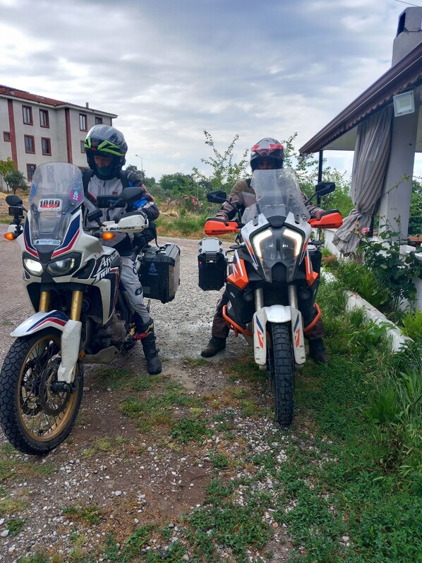 Two motorcycles parked on a gravel path with a building in the background. - Paradise House (Denizli)