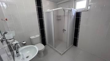 A bathroom with a toilet, sink, and shower.