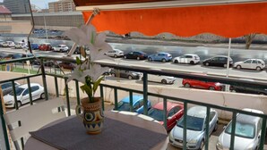 A balcony with a table and chairs, overlooking a parking area with various cars. - Sunny and central terrace apartment (Málaga)