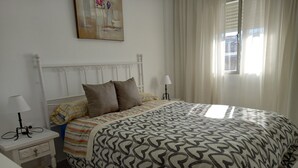 A neatly arranged bedroom with a bed, bedside tables, and a window with curtains. - Sunny and central terrace apartment (Málaga)