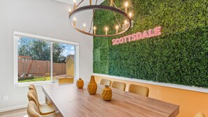 A dining area with a long wooden table, three vases, and a wall-mounted sign that reads "SCOTTSDALE". - Scottsdale Game House Heated Pool, Golf, Bowling (Scottsdale)