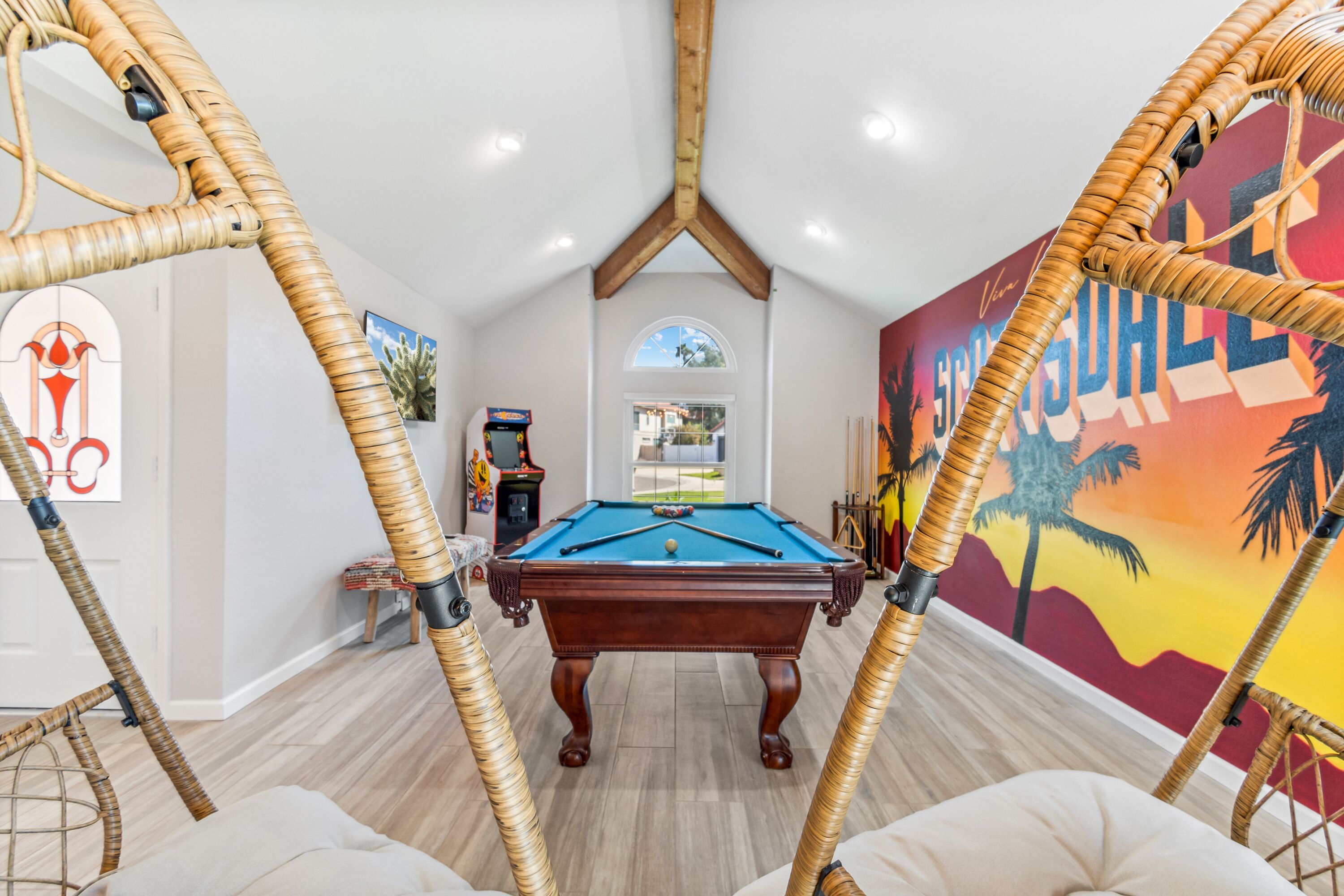 A pool table in a room with high ceilings and a view of the outdoors.