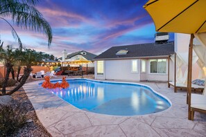 A backyard with a swimming pool, outdoor furniture, and a patio area.