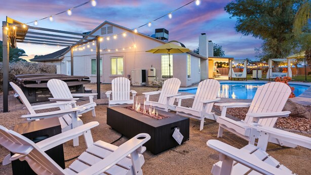 An outdoor patio with Adirondack chairs, a fire pit, and string lights. - Scottsdale Game House Heated Pool, Golf, Bowling (Scottsdale)
