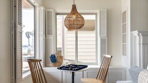 A room with a window, two wooden chairs, a small table, and a hanging light fixture.
