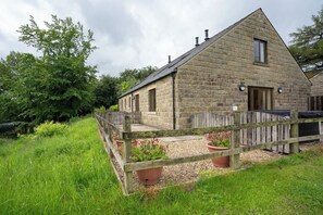 A stone building with a wooden fence, a door, and a window.