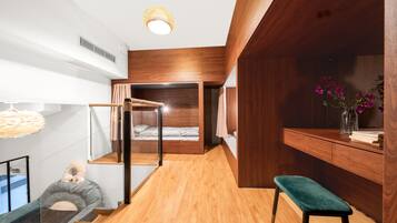 Un dormitorio moderno con suelo de madera, una litera, un escritorio con un florero y una lámpara colgante.