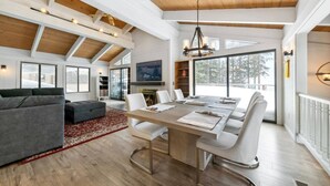 A spacious living area with a high ceiling, a dining table, and a fireplace. - Lake View Treasure -  Luxury with Lake Views (Incline Village)