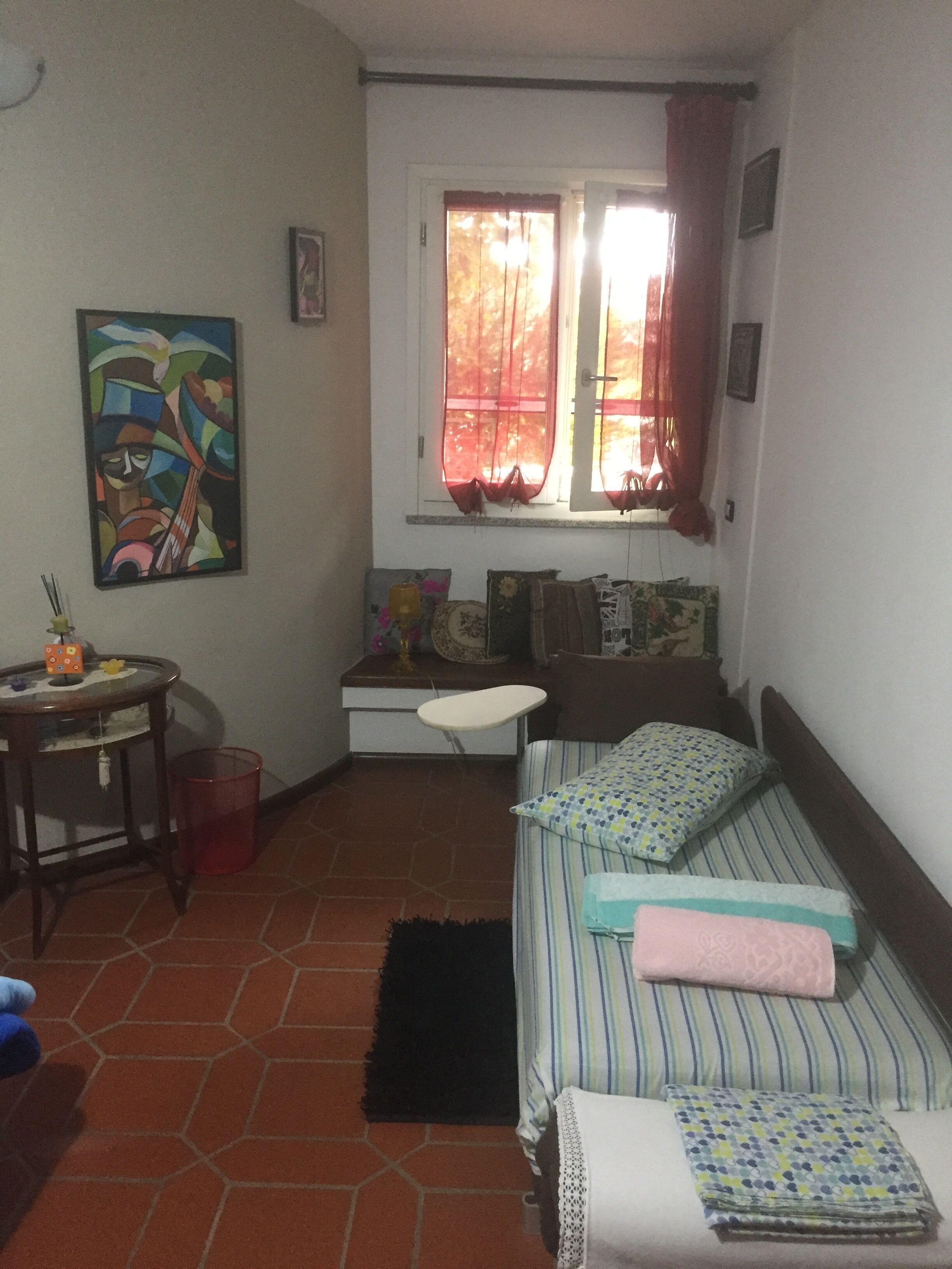 Ein kleiner, gemütlicher Raum mit einem Bett, einem Schreibtisch und einem Fenster mit Vorhängen.
