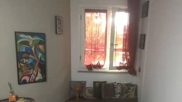 Ein kleiner, gemütlicher Raum mit einem Bett, einem Schreibtisch und einem Fenster mit Vorhängen.