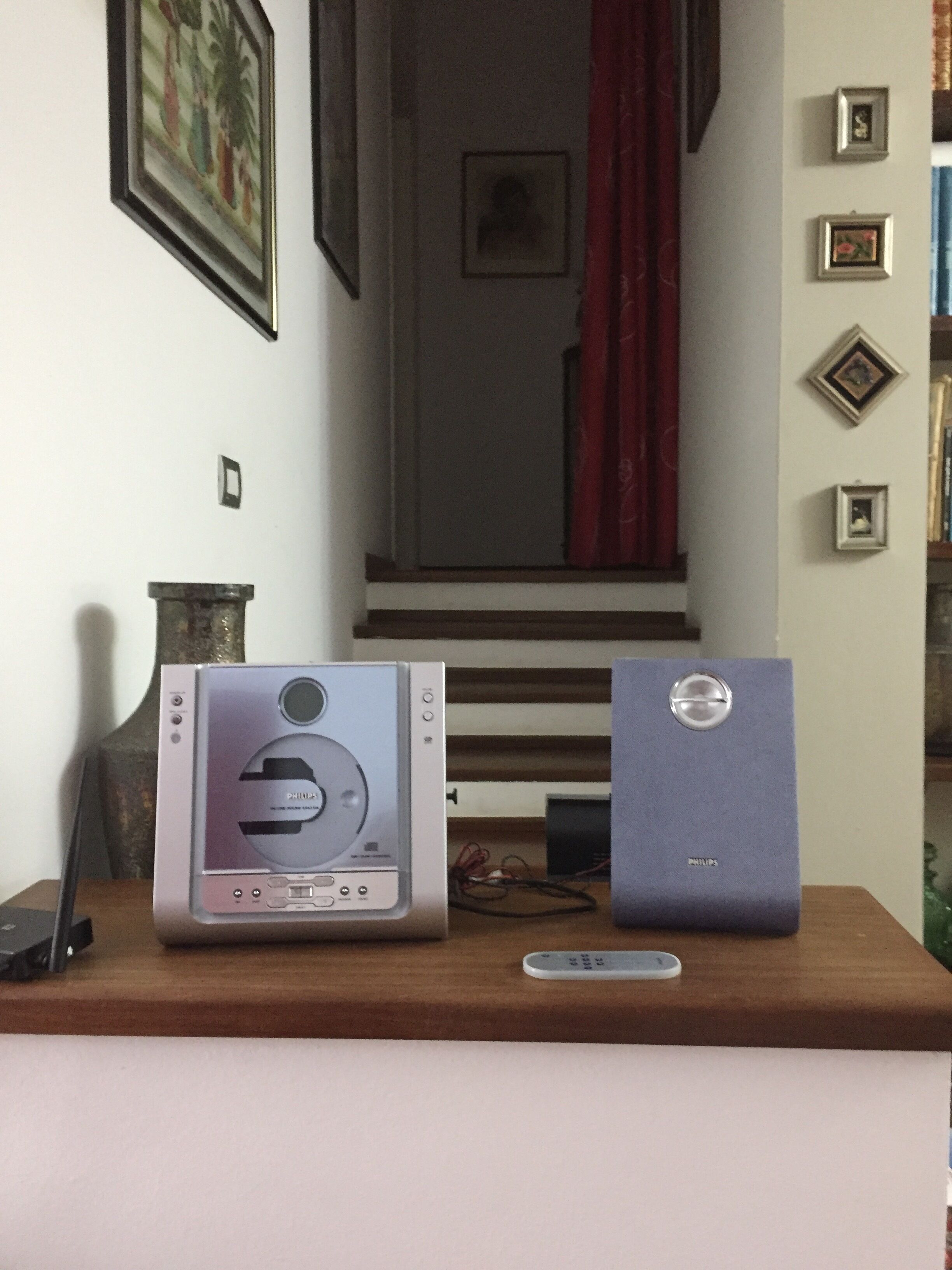 Une pièce avec un bureau en bois, une chaîne hi-fi Philips et un ordinateur portable.
