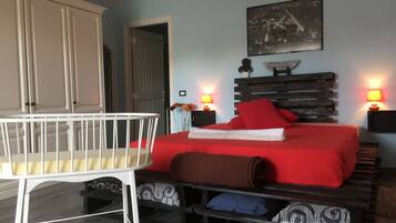 Une chambre à coucher avec un lit, des lampes de chevet, un berceau et une étagère fixée au mur.
