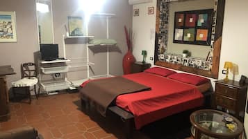 Ein Schlafzimmer mit einem Bett, einem Schreibtisch, einem Sessel, einem Fernseher und einem Spiegel.